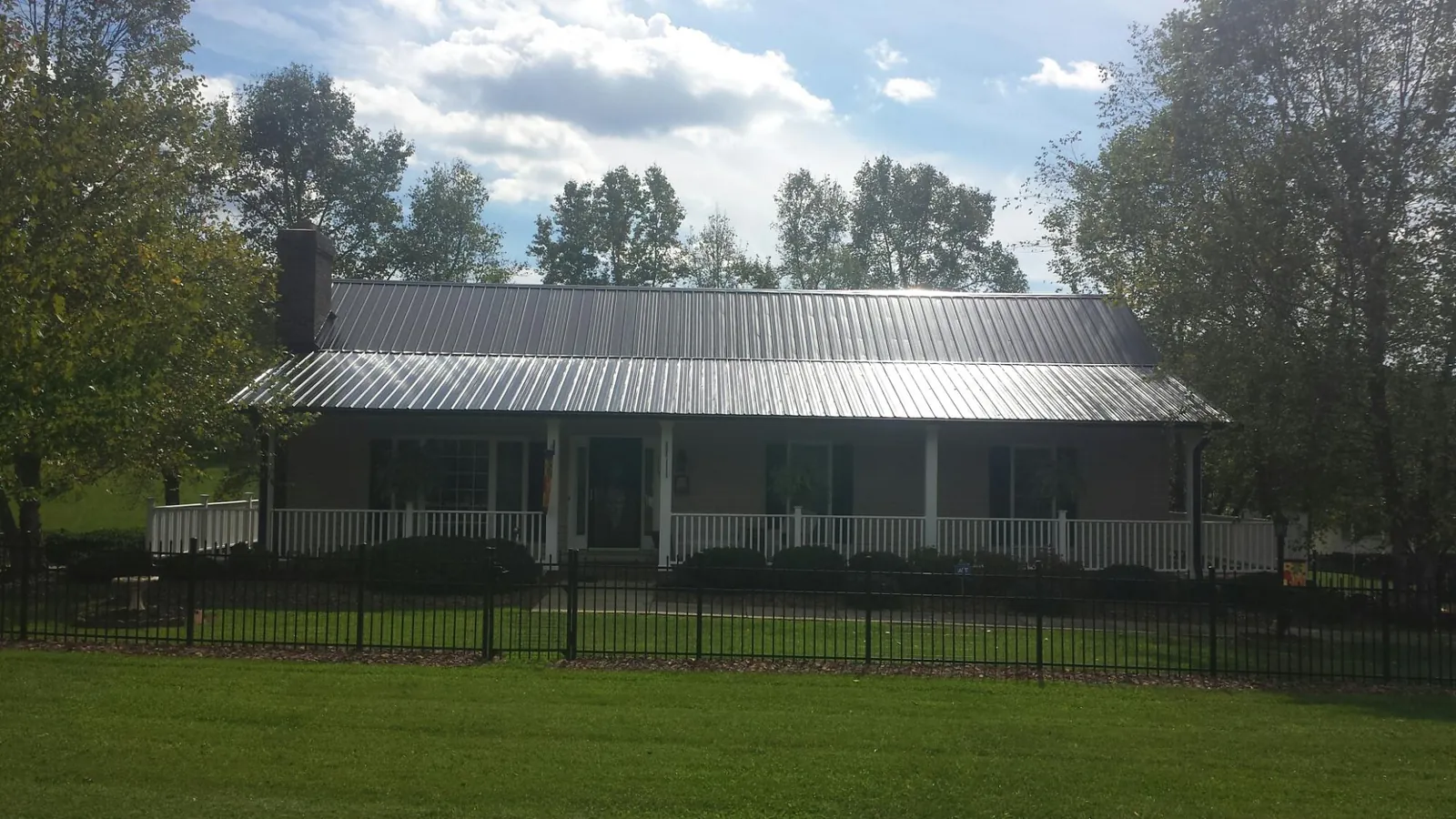 Gray metal roof on a brick ranch with a full width front porch — Gutter Guard Installation work by our crew in Neeses